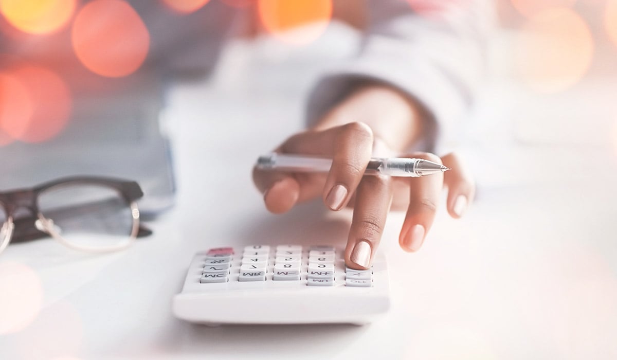 woman using calculator with glasses next to their hand